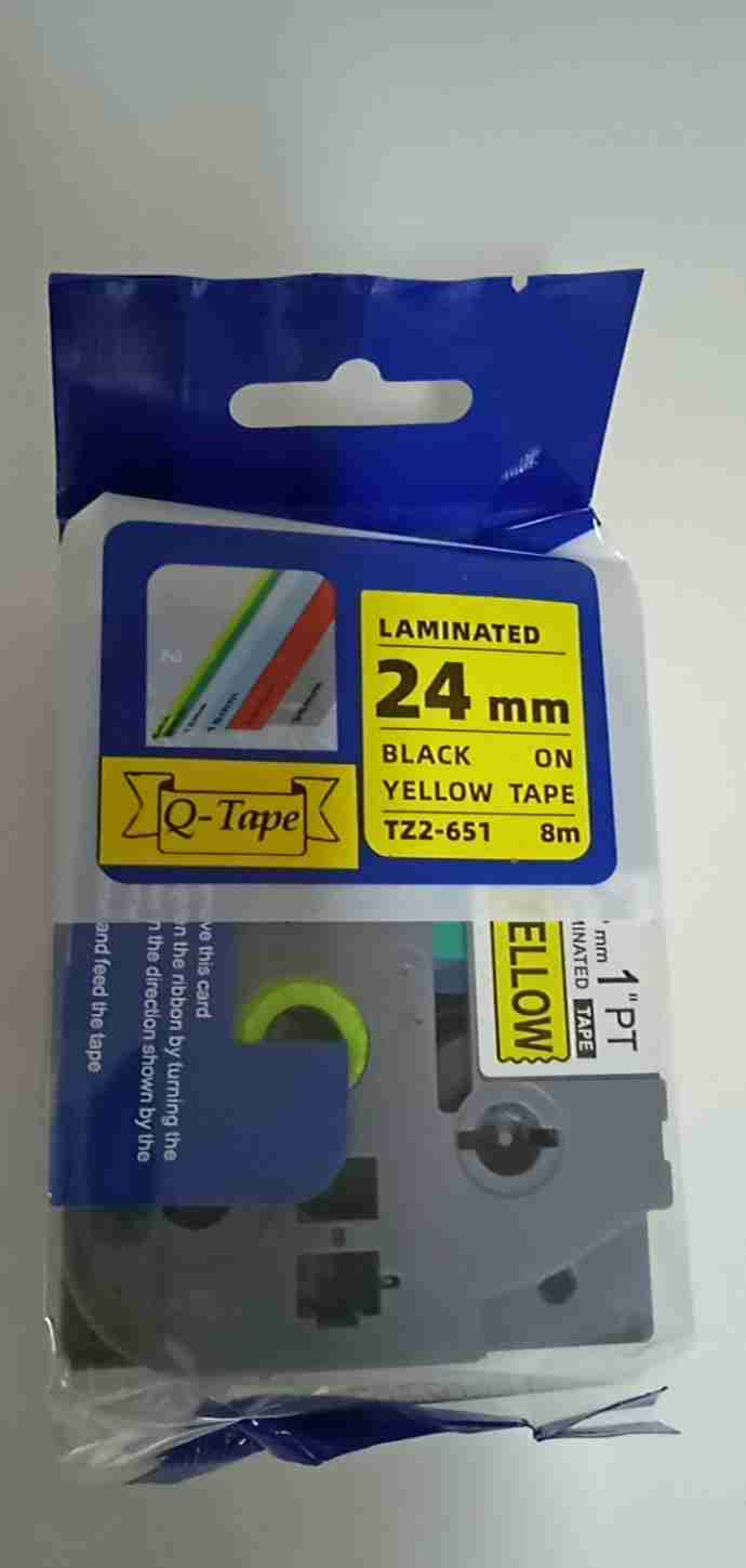 Compatible Brother TZ2-651 black on yellow 24mm label tape roll Brother P-Touch printer with 24mm yellow label installed Sample label printed with black on yellow TZ2-651 tape Compatible TZ2-651 label applied to warehouse shelf Close-up of laminated yellow label on electrical cable Packaging of Brother TZ2-651 compatible 24mm label tape