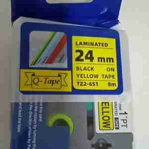 Compatible Brother TZ2-651 black on yellow 24mm label tape roll Brother P-Touch printer with 24mm yellow label installed Sample label printed with black on yellow TZ2-651 tape Compatible TZ2-651 label applied to warehouse shelf Close-up of laminated yellow label on electrical cable Packaging of Brother TZ2-651 compatible 24mm label tape